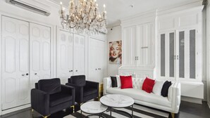 A modern living room with a white sofa, black armchairs, a chandelier, and a marble coffee table. - Roami at St. Helene (New Orleans)