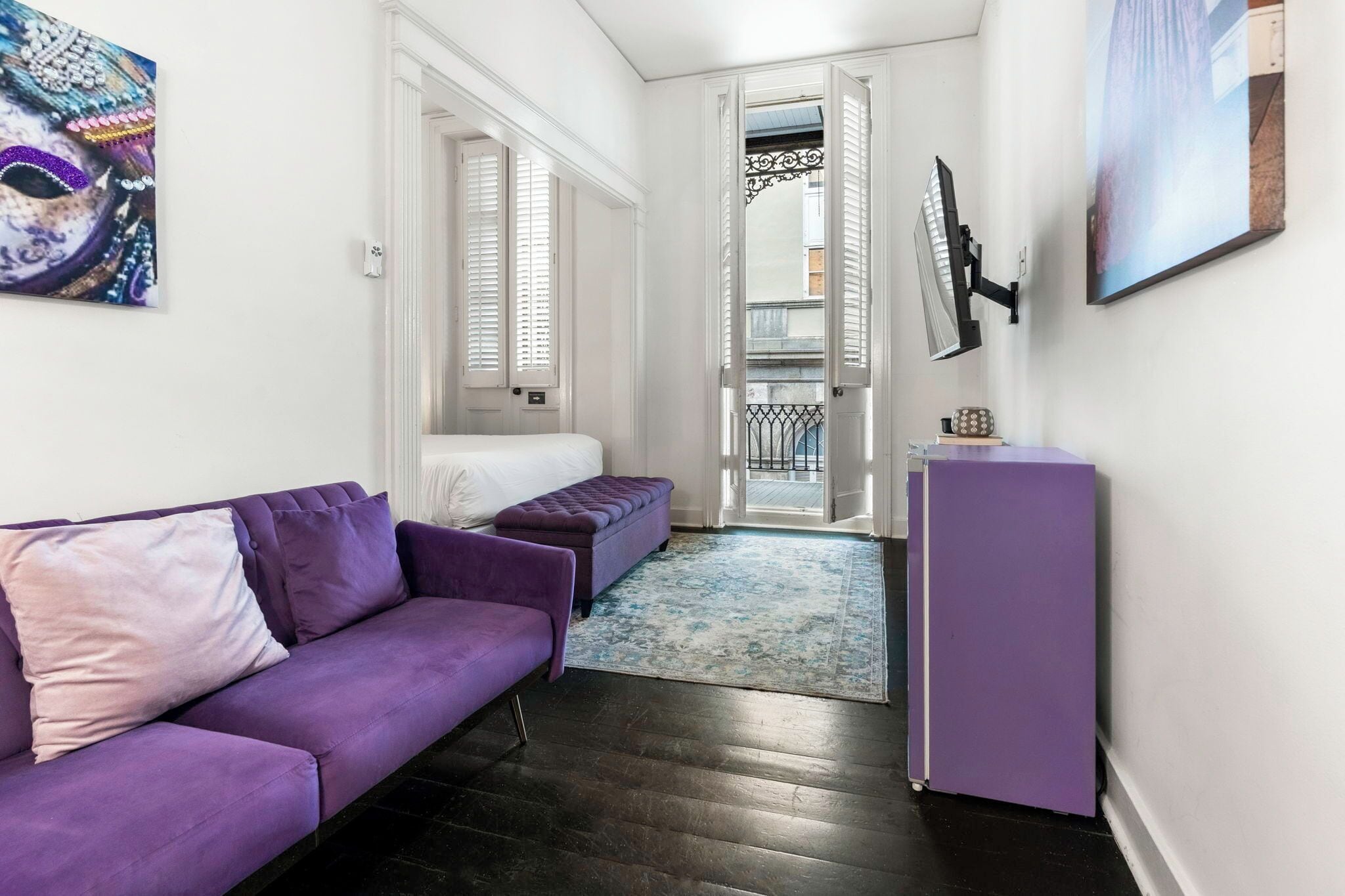 Una camera moderna con un divano viola, un tavolino, una televisione e un balcone con vista.