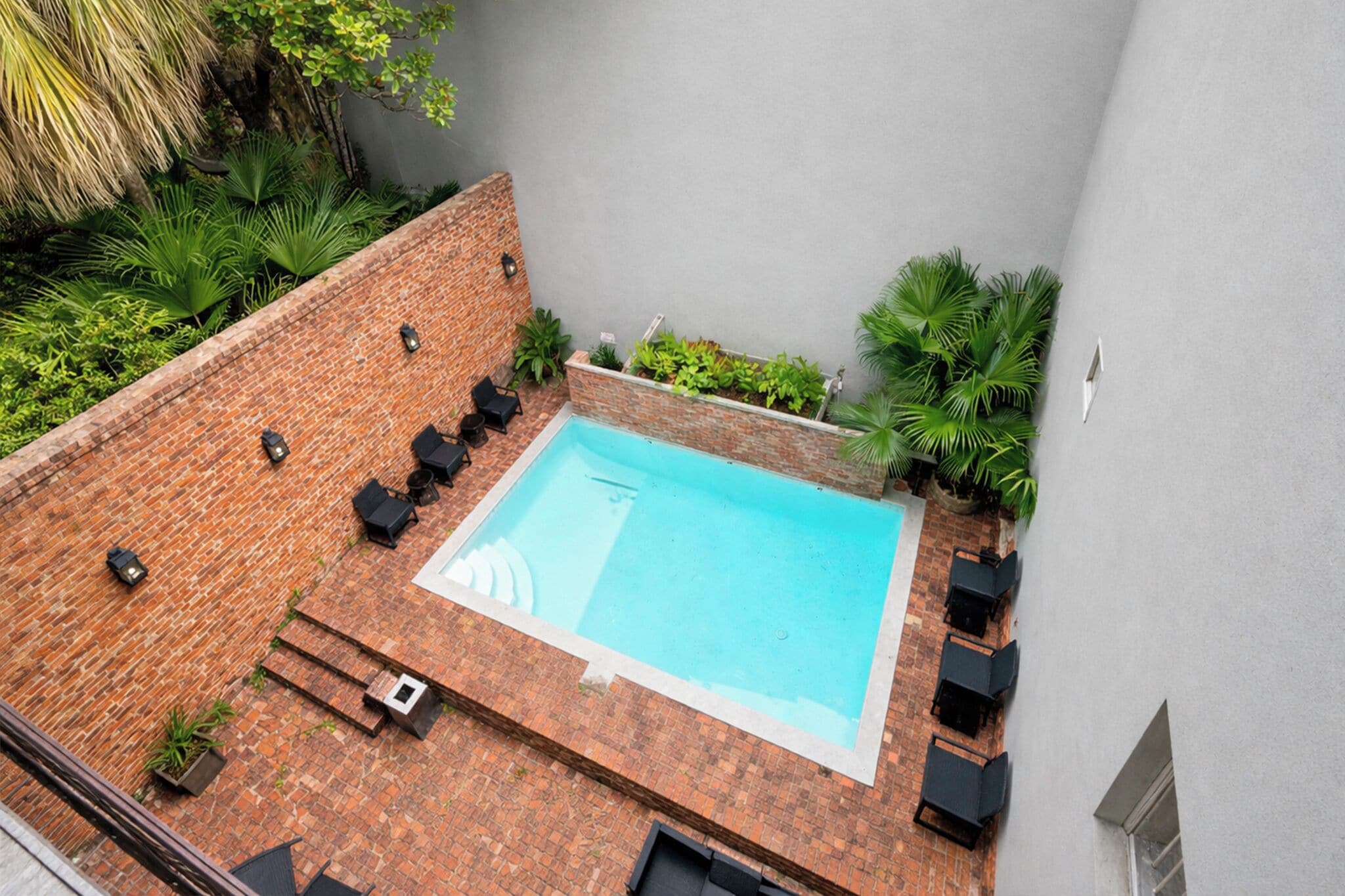 Ein Pool auf dem Dach mit Terassenboden, umgeben von Kübelpflanzen und Gartenmöbeln.