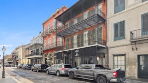 A row of historic buildings with balconies and a row of parked cars. - Roami at St. Helene (New Orleans)