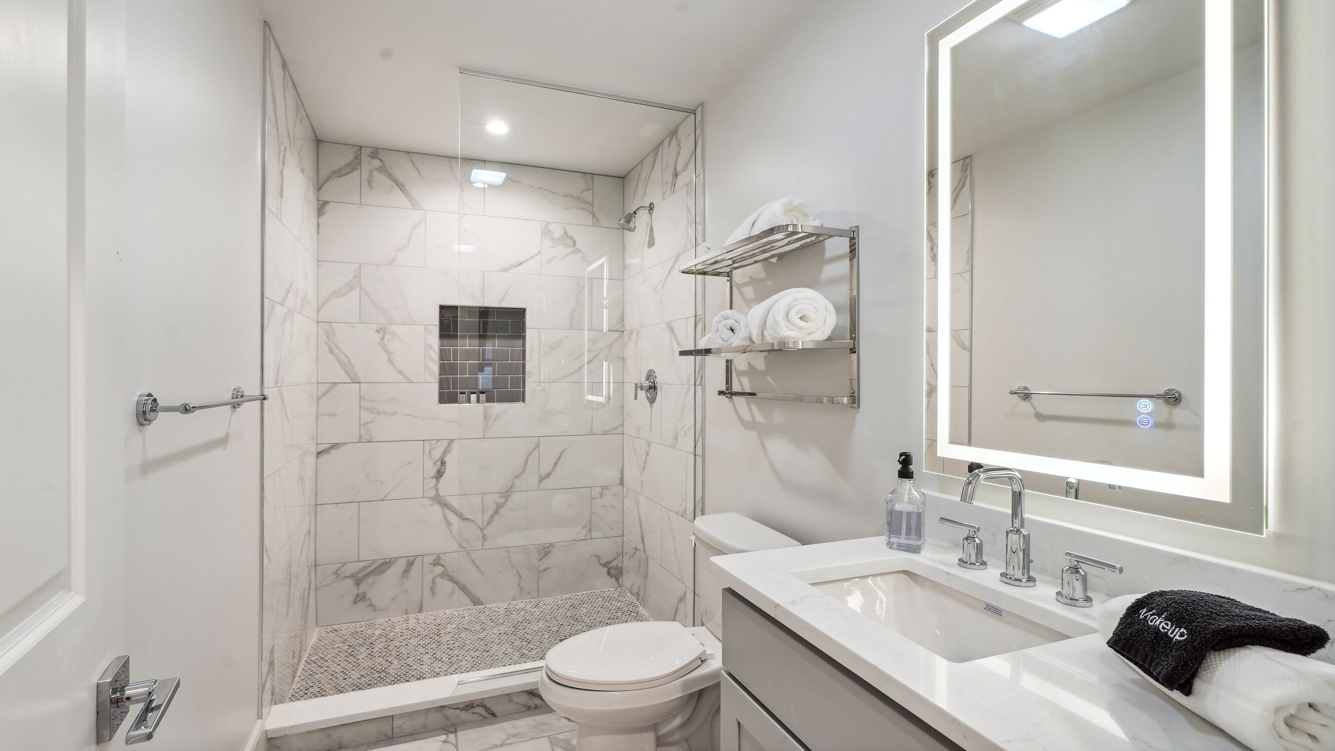 Une salle de bain moderne équipée d’une douche, de toilettes, d’un lavabo et d’un grand miroir.