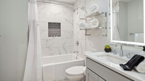 A modern bathroom with a bathtub, toilet, and a vanity with a mirror.