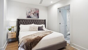 A modern bedroom with a tufted headboard, a large bed, a bedside table with a lamp, and a ceiling fan.