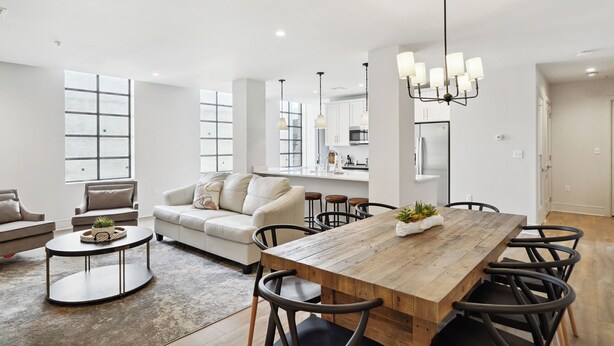 A modern living room with a wooden dining table, a sofa, and a coffee table.