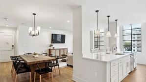 A modern kitchen with a large island, white cabinetry, and pendant lighting.