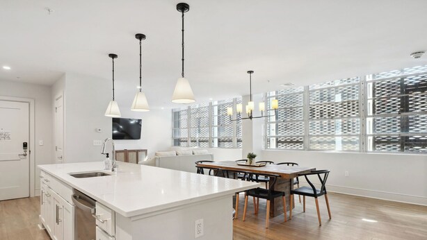 A modern kitchen with white cabinetry, a central island, pendant lighting, and large windows with a lattice design. - The Eleanor 6BD/4B - Sleeps 16 (New Orleans)