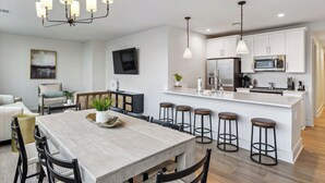 A modern kitchen with white cabinets, stainless steel appliances, and a central island with bar stools.