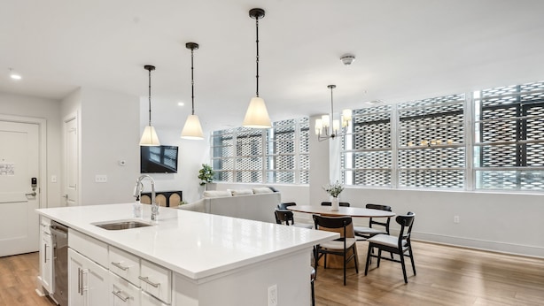 A modern kitchen with a large island, pendant lights, and a dining area with chairs and a table. - The Eleanor New Orleans 5BD/4B - All King Bedrooms (New Orleans)