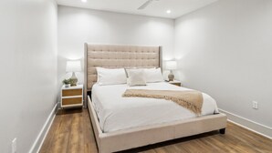 A bedroom with a large bed, a ceiling fan, bedside lamps, and a nightstand with a plant. - The Eleanor New Orleans 5BD/4B - All King Bedrooms (New Orleans)