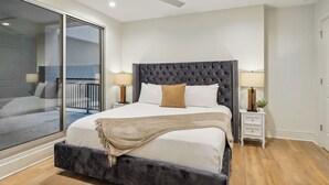 A modern bedroom with a large bed, a ceiling fan, and a view of a balcony. - The Eleanor 5BD/4B with Two Balconies (New Orleans)