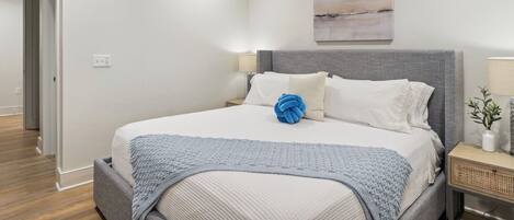 A modern bedroom with a bed, a ceiling fan, a nightstand, and a wall-mounted lamp.