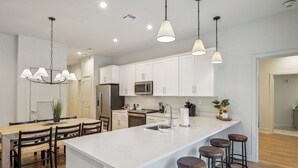 A modern kitchen with white cabinets, a marble island, and bar stools.