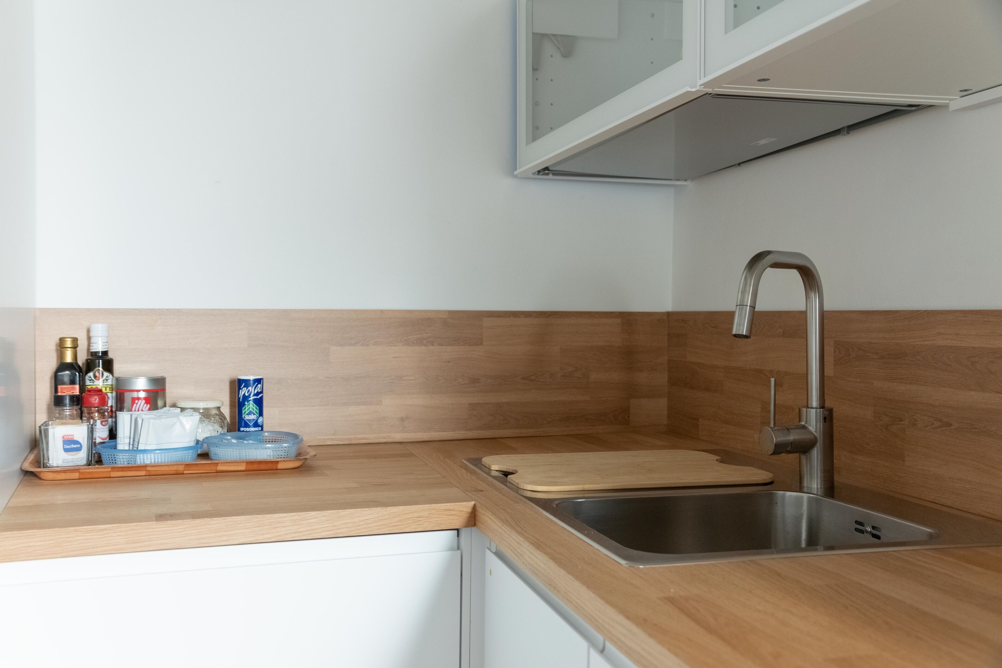 Une cuisine moderne dotée d’un plan de travail en bois, d’un évier en acier inoxydable et d’armoires.