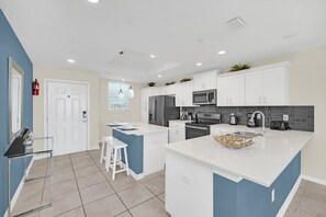 A modern kitchen with white cabinets, a central island, and a microwave. - Private Terrace • Bunk Room • Lazy River • Storey Lake • Near Disney (Kissimmee)