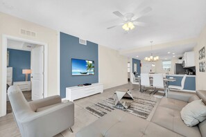 A modern living room with a TV, sofa, and dining area. - Private Terrace • Bunk Room • Lazy River • Storey Lake • Near Disney (Kissimmee)