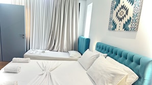 A hotel room with two beds, white linens, a blue headboard, and a geometric wall art piece. - Tirana Square Hotel (Tirana)