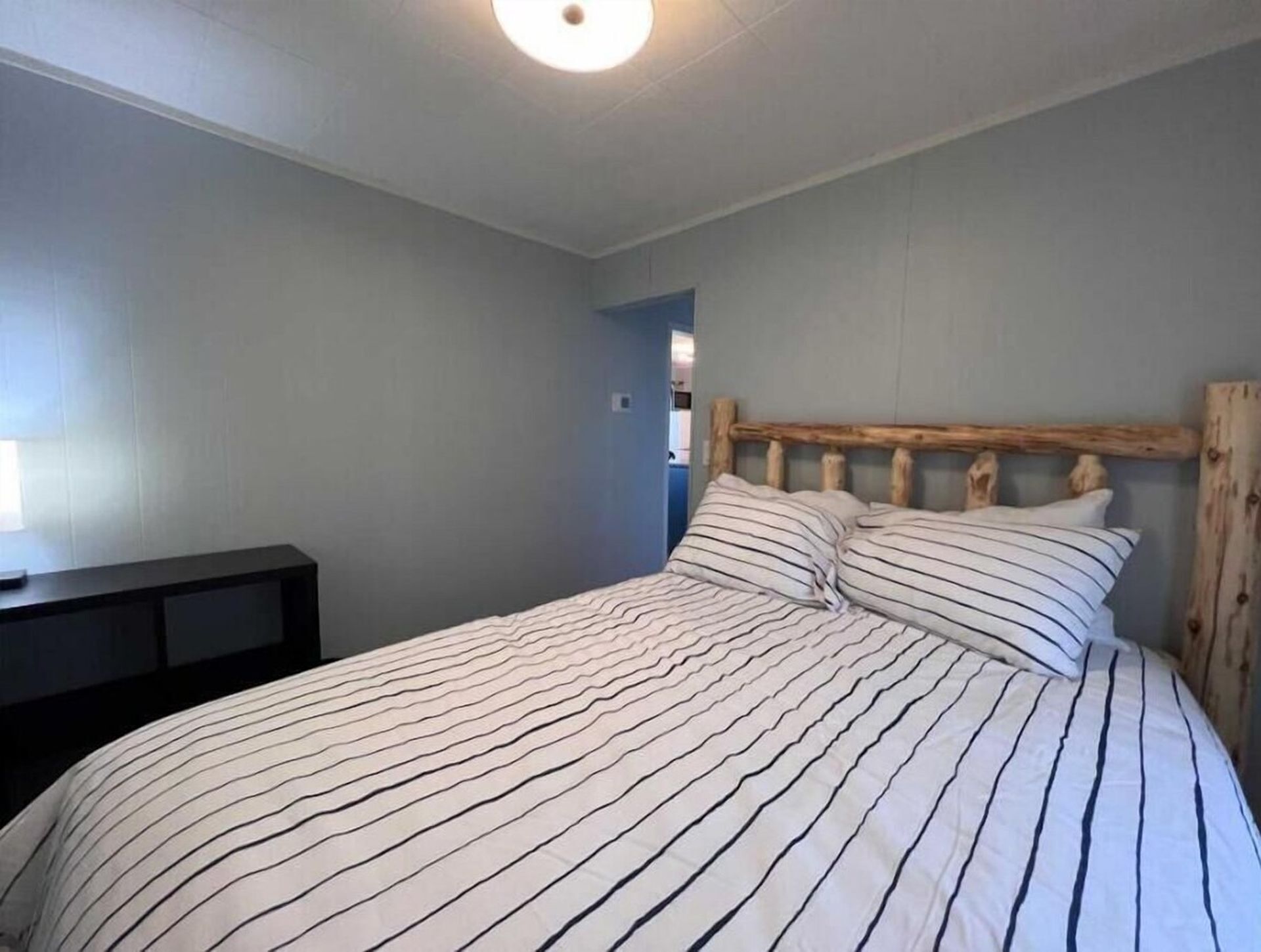 Une chambre à coucher avec un lit, une tête de lit en bois et une table de chevet.