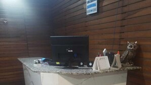 Uma receção com um computador, uma pequena estátua e um letreiro em cima.