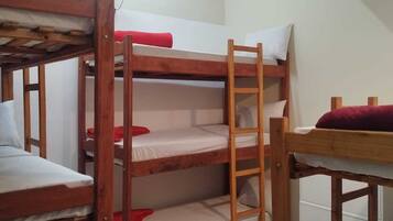 Quarto com beliche, ventilador de teto, paredes brancas e chão em azulejos.