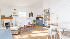 Un salon avec un canapé blanc, une table basse, une bibliothèque et une cheminée.