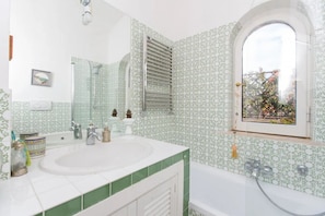 A bathroom with two sinks, a bathtub, a window with a view, and a towel rack. -  Attic for 2 with wonderful private terrace in Trastevere  (Roma)