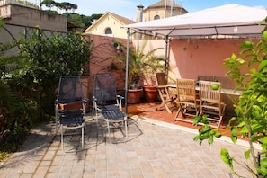 A patio with two metal chairs and a wooden table, surrounded by potted plants and a white canopy. -  Attic for 2 with wonderful private terrace in Trastevere  (Roma)