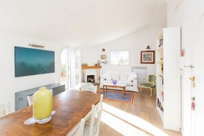 A bright living room with a fireplace, white furniture, and a large painting on the wall. -  Attic for 2 with wonderful private terrace in Trastevere  (Roma)