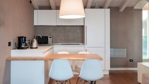 A modern kitchen with white cabinets, a wooden countertop, and a hanging light fixture. - WOW what a view! Charming apartment with terrace, pool and fitness center (Salo')