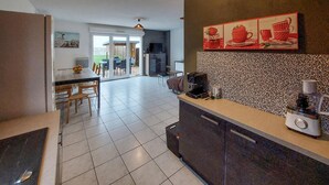 A modern kitchen with a dining area, a coffee machine, and a patterned backsplash.