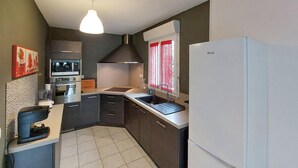A compact kitchen with a white refrigerator, a built-in oven, a microwave, and a sink.