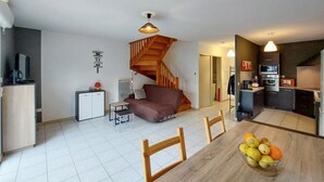A compact living space with a dining area, kitchenette, and a staircase.