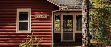 A red log cabin with a sign reading "Lake View" and a small porch.