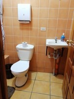 Un baño pequeño con inodoro, lavamanos y secador de manos.