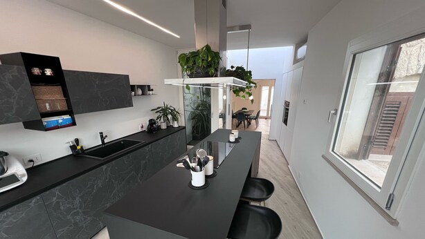 A modern kitchen with a black countertop, a built-in sink, and a window overlooking the street.