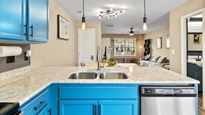 Una cocina con armarios azules, una encimera blanca y un lavavajillas.