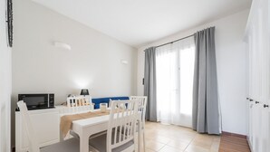 Une pièce moderne et bien éclairée, équipée d’une table à manger, de chaises, d’un four à micro-ondes et d’un téléviseur.