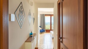 Un couloir menant à un balcon avec vue, une chaise bleue et une porte en bois.