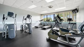 Un gimnasio con cintas de correr, elípticas y una escaladora.