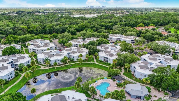 An aerial view of a residential complex with multiple buildings, a central swimming pool, and surrounding greenery. - 3919 Orlando Vacational Apartment (Orlando)