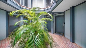A building with a central atrium, a palm tree, and a brick floor. - 3919 Orlando Vacational Apartment (Orlando)