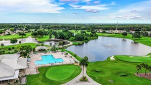 A golf course with a swimming pool, a pond, and a clubhouse. - 3919 Orlando Vacational Apartment (Orlando)