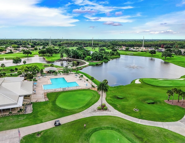 A golf course with a swimming pool, a pond, and a clubhouse. - 3919 Orlando Vacational Apartment (Orlando)