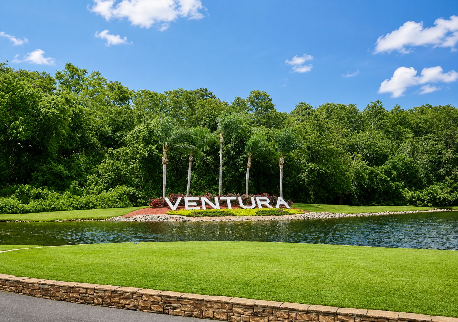 A landscaped area with a pond, a sign reading 'VENTURA,' and a stone wall.