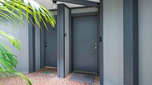 A closed grey door with a number plate, a metal handle, and a small window. - 3919 Orlando Vacational Apartment (Orlando)