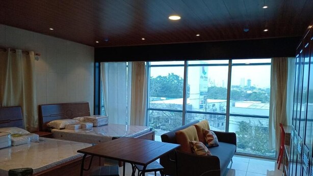A modern hotel room with a bed, a sofa, a dining table, and a view of the city. - Hospedaje Ciste (Panama City)