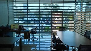 A conference room with a large window, a table, chairs, and a computer desk. - Hospedaje Ciste (Panama City)