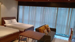 A hotel room with two beds, a small table, and a sofa. - Hospedaje Ciste (Panama City)