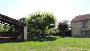 A grassy yard with a tree, a stone building, and a covered structure. - L'oustal Bergounhou (Le Bas-Ségala)