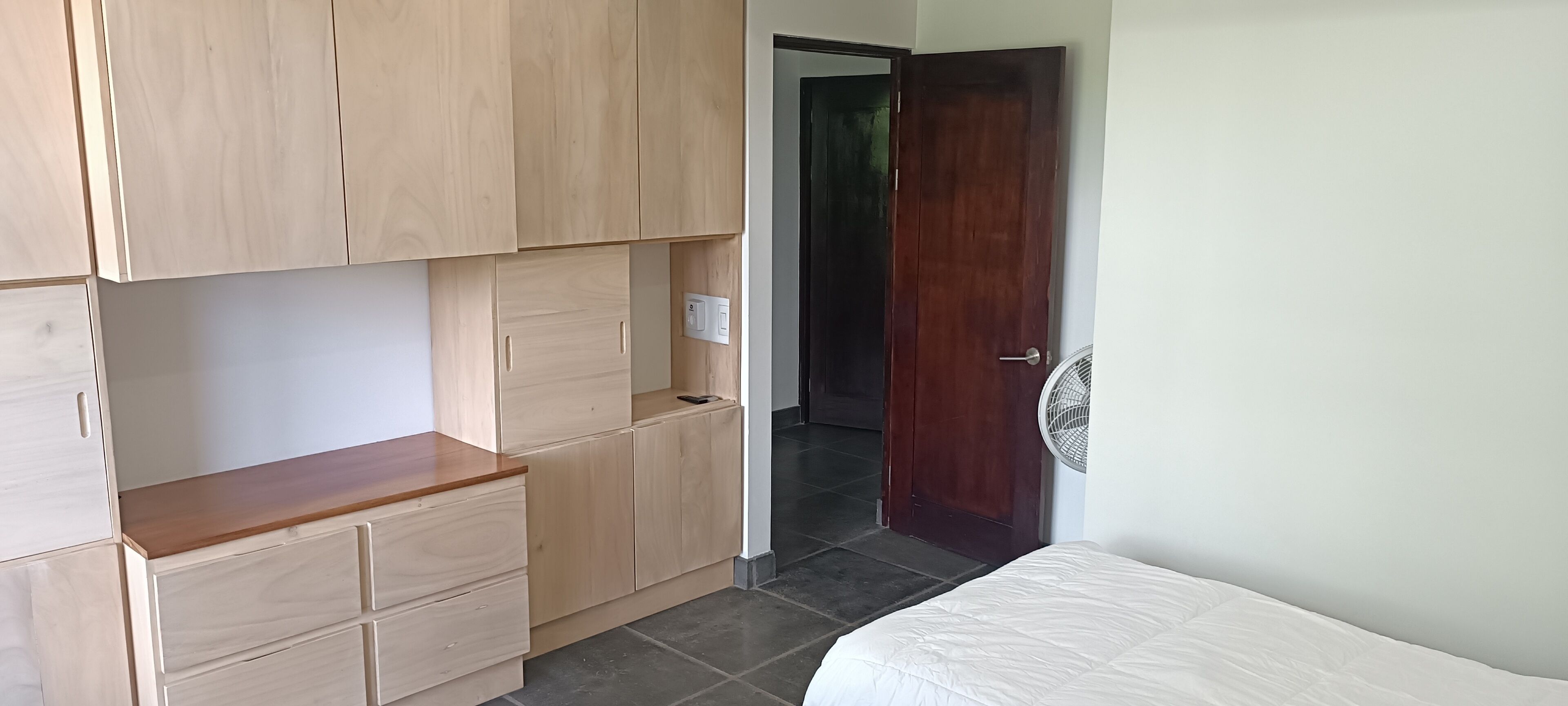 Ein Schlafzimmer mit einem Bett, einem Holzschrank und einer Tür zu einem anderen Raum.