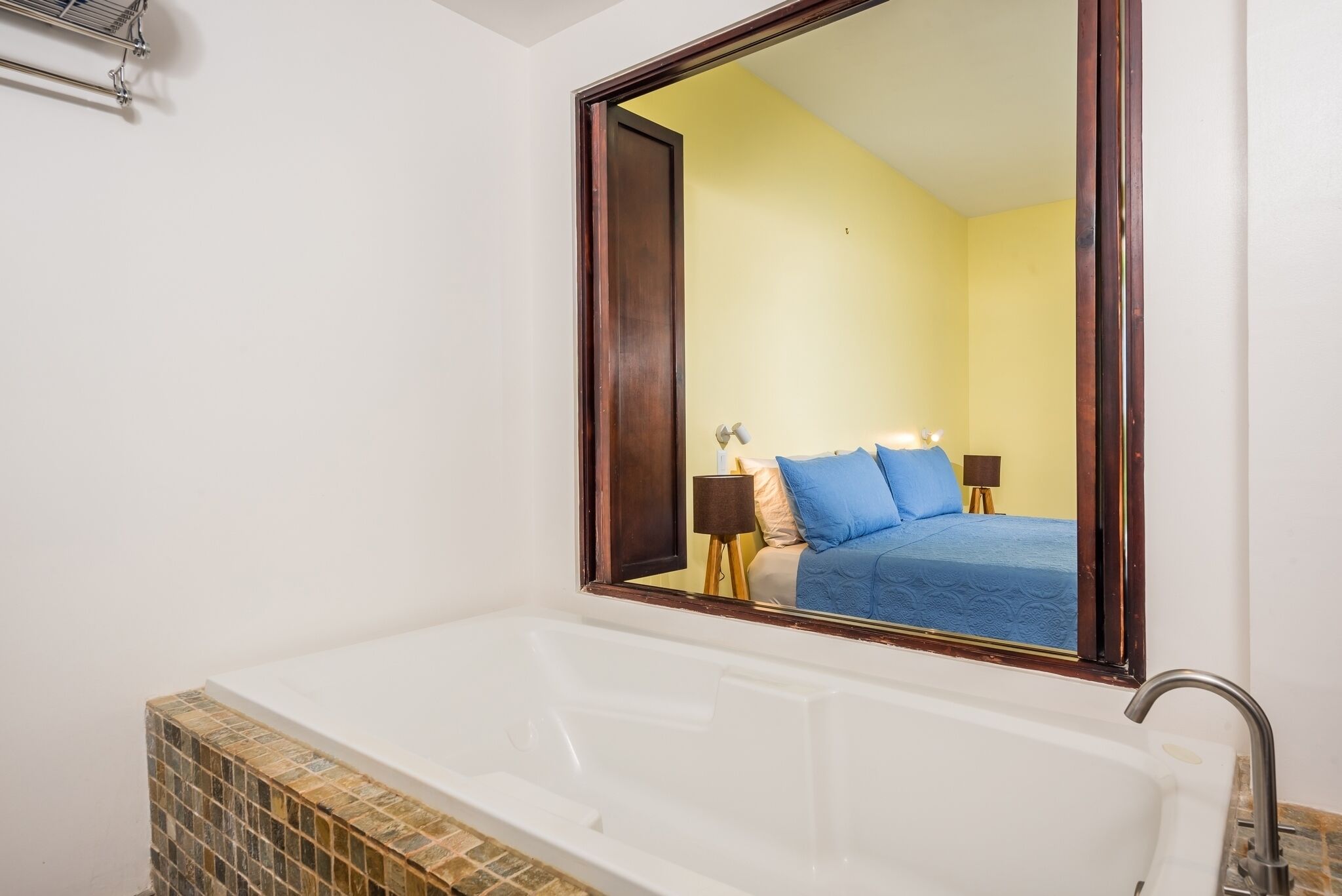 Une salle de bain avec une grande baignoire, un miroir et un sol carrelé.